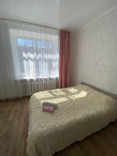 Un dormitorio con una cama grande y una ventana en Квартира-студия недорого напротив парка Металлургов, en Öskemen