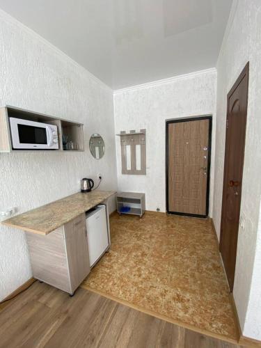 - une petite cuisine avec un comptoir et un four micro-ondes dans l'établissement Квартира-студия недорого напротив парка Металлургов, à Öskemen