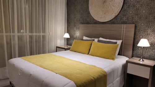 1 dormitorio con 1 cama grande con almohadas amarillas en Be Haus Temporary Apartments en San Luis