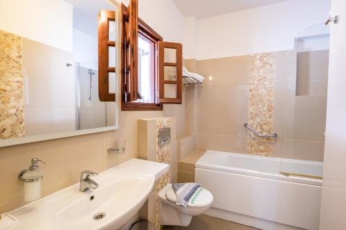 a bathroom with a sink and a toilet and a tub at Aphrodite Luxury Studios & Apartments in Karpathos