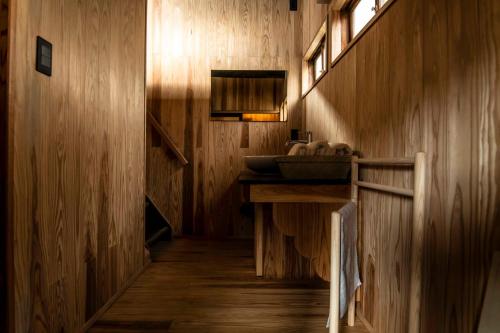 a bathroom with a sink and a wooden wall at Nipponia 甲佐 疏水の郷 in Kosa
