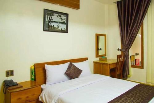 a bedroom with a white bed and a mirror at Duy Thảo Hotel in Da Lat