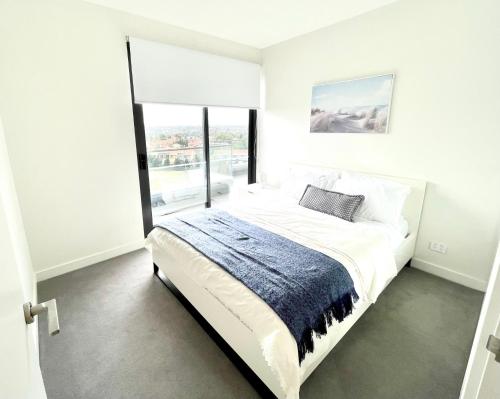 um quarto branco com uma cama grande e uma janela em 2 Bed 2 Bathroom Penthouse With Amazing Balcony & City Views - Across From Highpoint em Maribyrnong