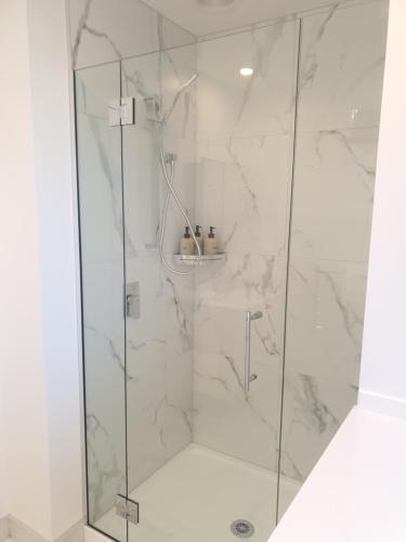 a bathroom with a shower with white marble at Modern CBD, Walk to Te Pae, Across from Casino, FREE Parking in Christchurch
