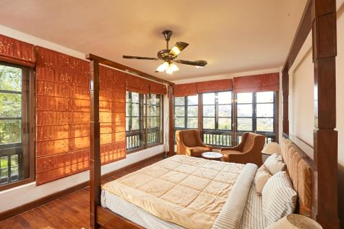 um quarto principal com uma cama e janelas em Bandipur Bliss -- Villa - Hotel - Apartment - Cottage em Tanahun