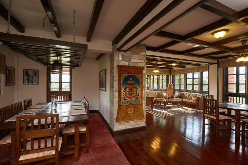 uma sala de jantar com mesas e cadeiras de madeira em Bandipur Bliss -- Villa - Hotel - Apartment - Cottage em Tanahun
