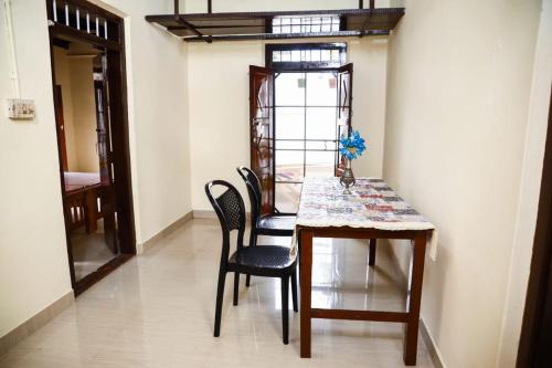 a dining room table and chairs in a room at Bobbys Corner in Alleppey