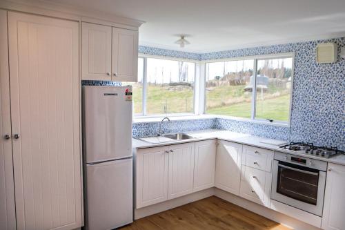 a kitchen with a white refrigerator and a window at Taieri Bank Cottage - Middlemarch, Otago in Middlemarch