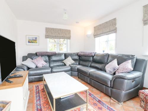 a living room with a black leather couch at Highfield House in Leek