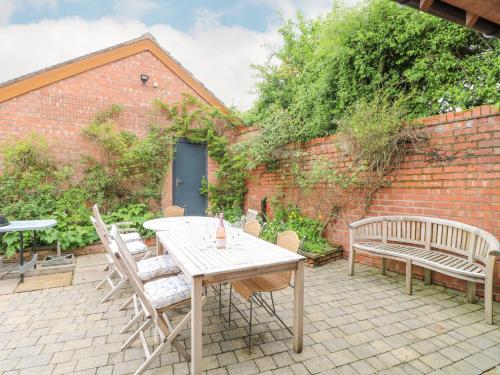 a patio with a table and chairs and a brick wall at Highfield House in Leek