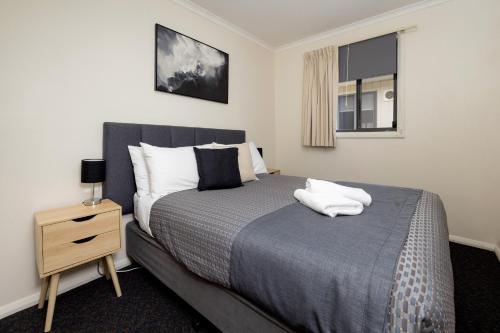 a bedroom with a bed with two white towels on it at BIG4 Hobart Airport Tourist Park in Cambridge