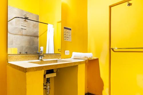 a yellow bathroom with a sink and a mirror at Gagaka Rua hostel in Santa Marta