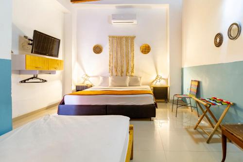 a bedroom with two beds and a tv on the wall at Gagaka Rua hostel in Santa Marta