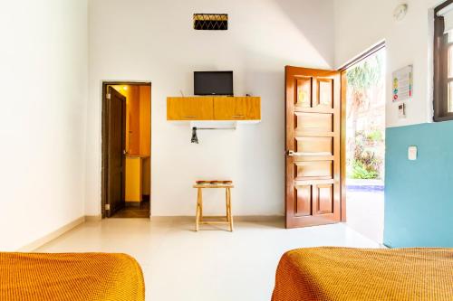 a bedroom with two beds and a television on the wall at Gagaka Rua hostel in Santa Marta
