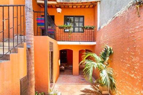 an orange house with a balcony and a palm tree at Gagaka Rua hostel in Santa Marta