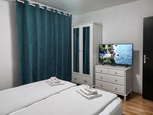 a bedroom with two beds and a tv and a dresser at Apartament Alina in Deva