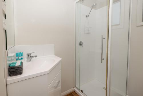 a white bathroom with a sink and a shower at BIG4 Hobart Airport Tourist Park in Cambridge