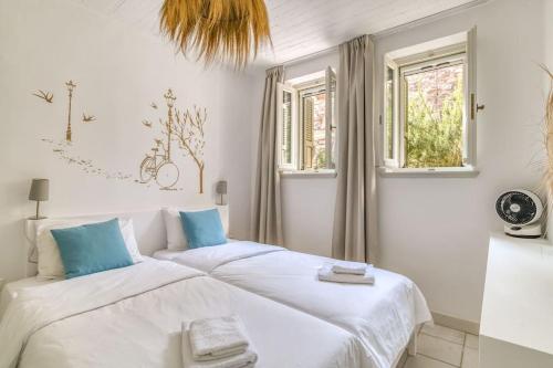 a bedroom with a large bed with white sheets and blue pillows at Villa Vino - Cycladic Calm in Isterni