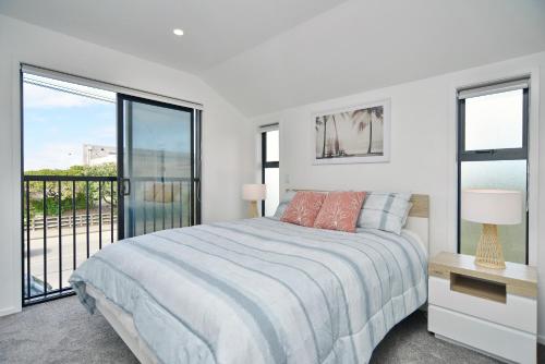 a white bedroom with a bed and a balcony at Sea air and Sandy Beach, beautiful 1 bed 1 bath in Christchurch