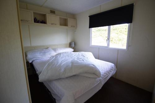 - une chambre avec un lit doté de draps blancs et une fenêtre dans l'établissement Lovely 4 Berth Caravan For Hire At Sunnydale Holiday Park Ref 35225kc, à Louth