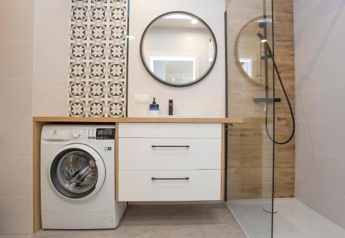 ein Badezimmer mit einer Waschmaschine und einem Spiegel in der Unterkunft Urban Jungle apartament Emily in Białystok