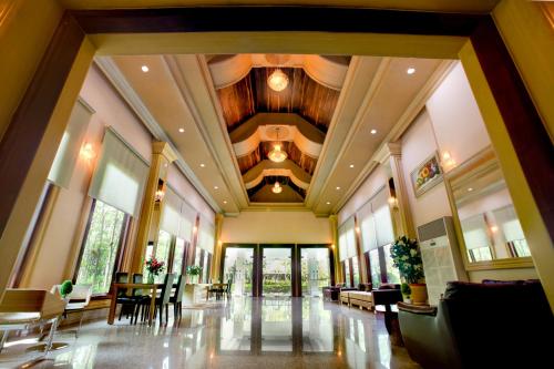 a large lobby with a wooden ceiling and tables and chairs at Pearl Resort & Hotel in Nonthaburi