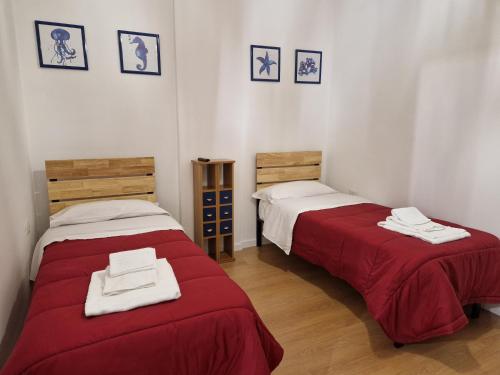 - 2 lits dans une chambre avec des draps rouges et blancs dans l'établissement IL FARO in centro vicino Pompei Amalfi Sorrento, à Castellammare di Stabia