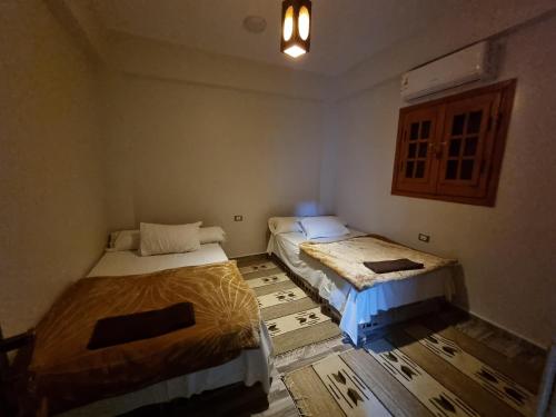 a room with two beds in a room with a wooden floor at SEMIRAmis Siwa in Siwa