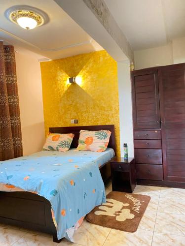 um quarto com uma cama e uma parede amarela em N-E Studio meublé 2 em Douala