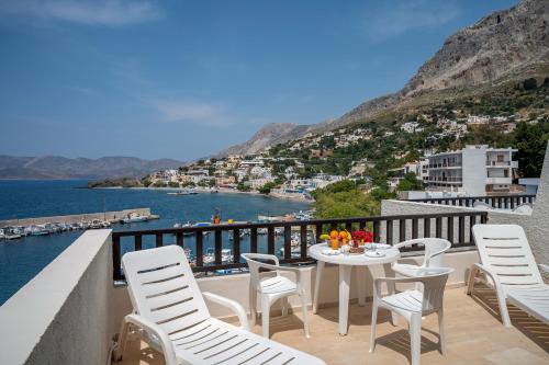 balcón con mesa, sillas y vistas al agua en Pelagos Seafront Accommodation - Maria, en Myrties