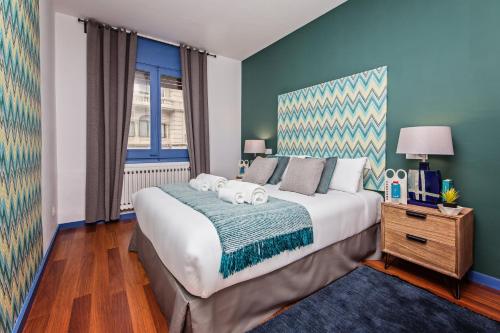 1 dormitorio con 1 cama grande y pared azul en Sweet Inn - Diagonal - Francesc Macia, en Barcelona