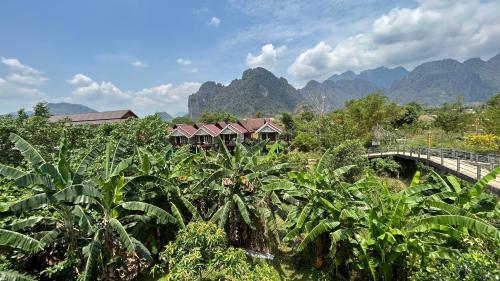 a bridge over a banana field with mountains in the background at Domon Riverside Hotel in Vang Vieng