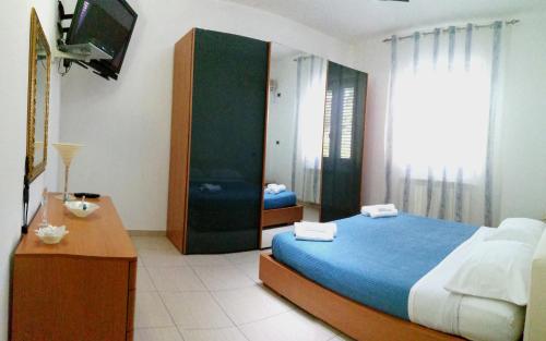 Schlafzimmer mit einem Bett, einem Schreibtisch und einem TV in der Unterkunft Heraclea Home in Roseto Capo Spulico