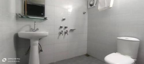 a white bathroom with a sink and a shower at Hotel Crown City in Chittagong