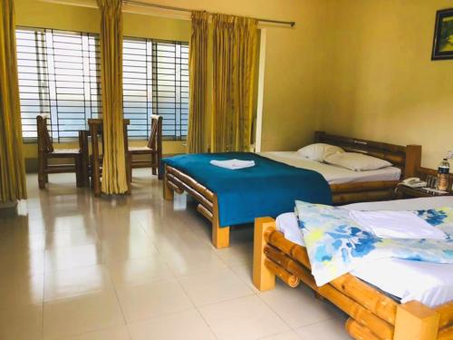 スリーマンガルにあるTea Heaven Resortのベッド2台、テーブルと椅子が備わるホテルルームです。