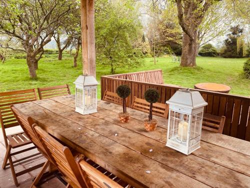 een houten tafel met 3 lantaarns op een patio bij Beautiful 5 bedroom house with hot tub & fire pit in Abergavenny