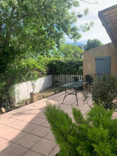 een patio met een tafel en stoelen en een hek bij Maison Bouchou in Eyguières