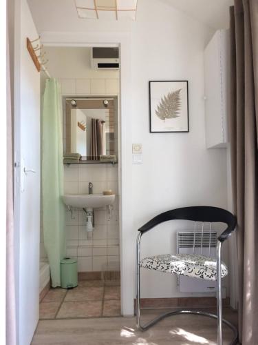 La salle de bains est pourvue d'une chaise noire et d'un lavabo. dans l'établissement Nuitée Naturopathique, à La Rochelle