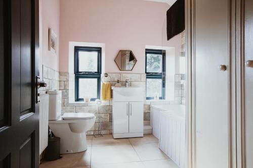 y baño con aseo, bañera y lavamanos. en Beautiful 5 bedroom house with hot tub & fire pit, en Abergavenny