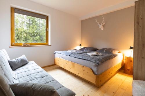 a bedroom with a bed and a couch and a window at Bergkristall Ruhe und Aussicht auf 1100m in Sankt Lorenzen ob Murau