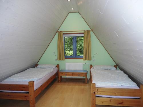 2 Betten in einem schrägen Zimmer mit Fenster in der Unterkunft Ferienhaus Nr 16 am Twistesee in Bad Arolsen