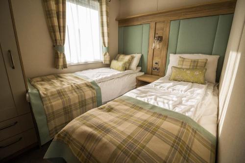 Cette petite chambre comprend 2 lits et une fenêtre. dans l'établissement Luxury Lodge With Stunning Full Sea Views In Suffolk Ref 20234bs, à Hopton on Sea