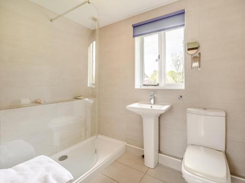 a bathroom with a toilet and a sink and a tub at The Coach House in Aldington