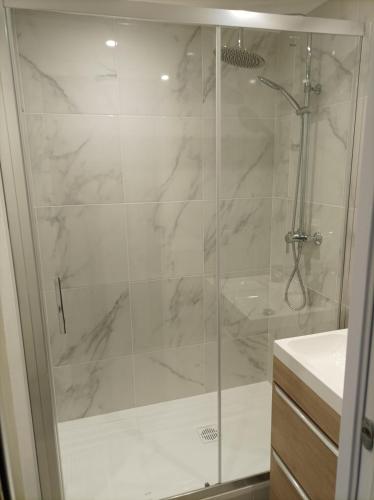 une douche avec une porte vitrée dans une salle de bain dans l'établissement Charmant studio dans la résidence Haut du Golf, à Valescure