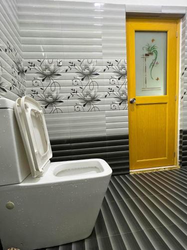 a bathroom with a toilet and a yellow door at Sigiriya Green Garden Home in Sigiriya