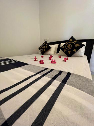 a bed with black and white sheets and pink flowers on it at Sigiriya Green Garden Home in Sigiriya