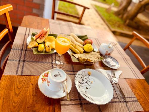a table with a plate of food and a cup of orange juice at Sigiriya Green Garden Home in Sigiriya
