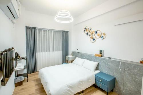 a bedroom with a white bed and a tv at 安平包棟民宿 - 尋雨 - 部分日期可預定散房-台南民宿園景採光豪宅 in Tainan