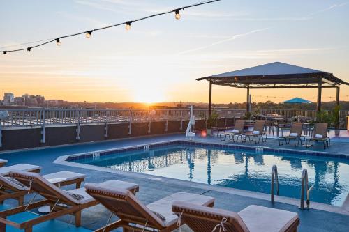 a pool on the roof of a building with chairs and a sunset at The Ven at Embassy Row, Washington, D.C., a Tribute Portfolio Hotel in Washington, D.C.