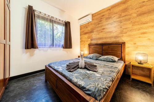 1 dormitorio con 1 cama y pared de madera en VILLA L HORIZON 4 appartements avec piscine, en Petite Île